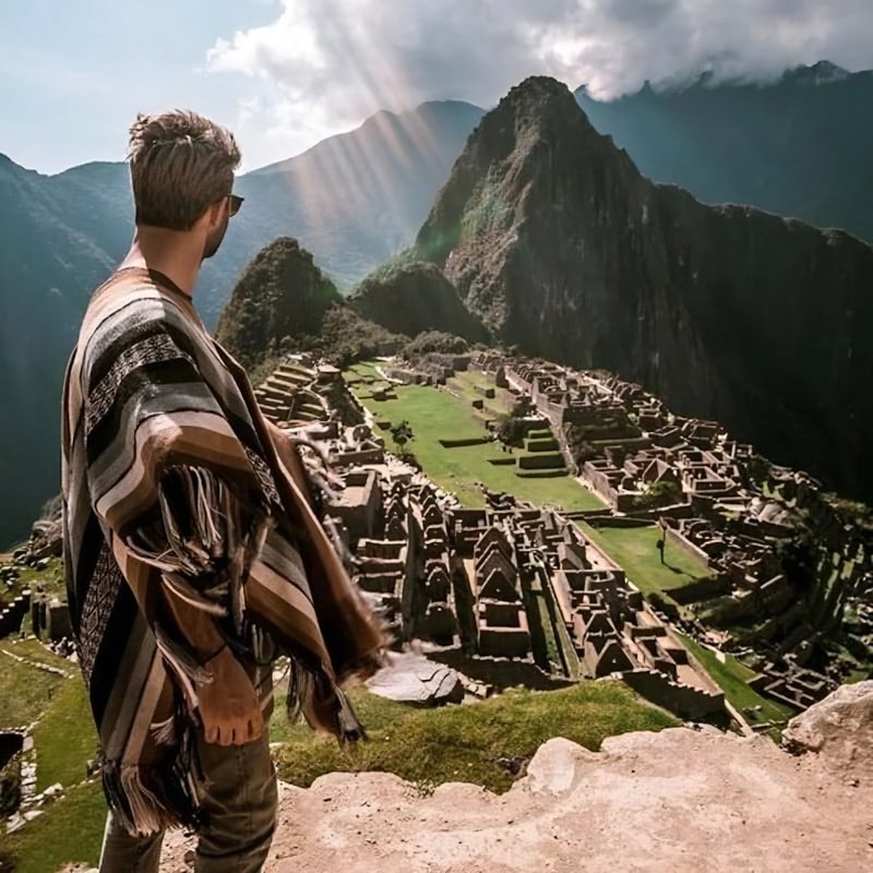 Homme au poncho devant le Machu Picchu